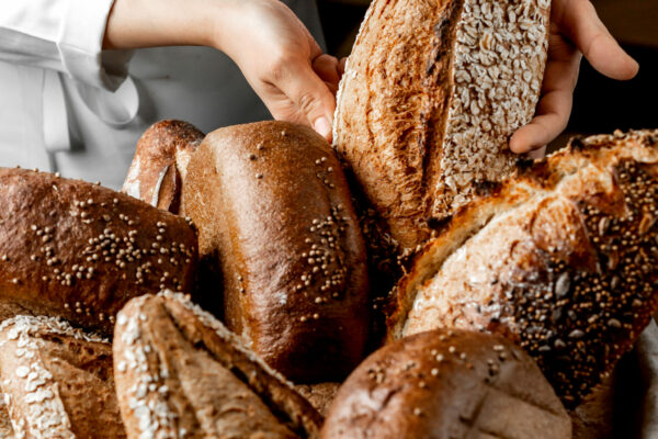 woman putting whole grain bread bun among other breads